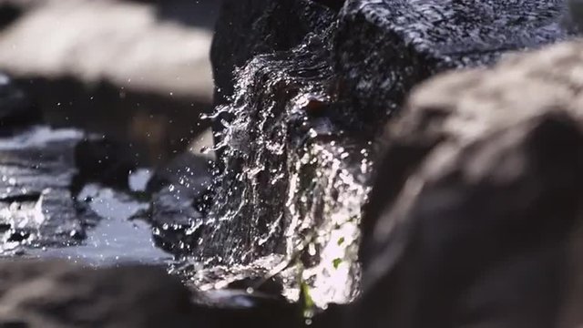 Close-up slow motion shot of water cascading over rocks.