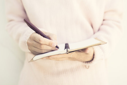 She writes something in notebook closeup