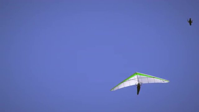 Shot of hang glider and paraglider in the air near eachother.