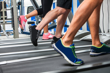 Group of legs wearing sneakers running on treadmill  at sport gym.