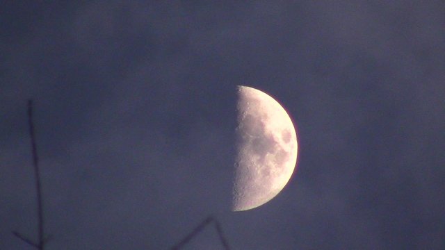 clouds passing over half moon at dusk