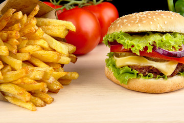 Cheeseburger,french fries with in the bar on wooden desk on black