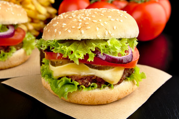 Big cheeseburgers on paper on black