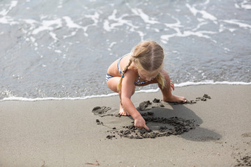 Little girl  sitting on the beach.