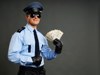 Policeman in uniform holds money in hands and shows thumb up