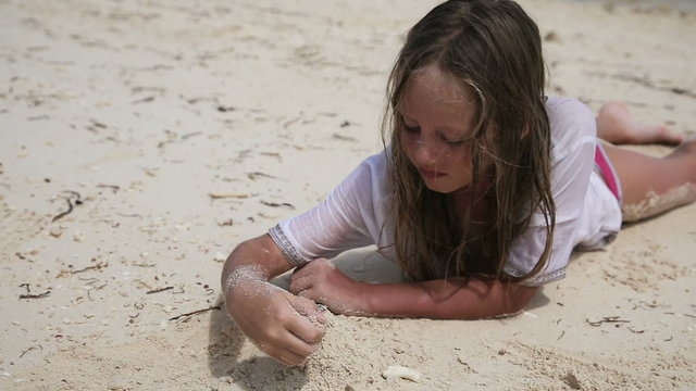 Happy child playing with sand on beach in summer.