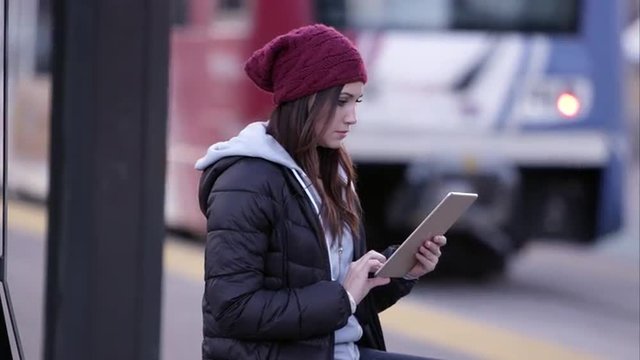 Woman using tablet while sitting at trax stop.