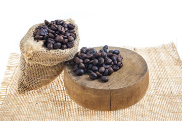 Coffee beans in sack on wooden cutting board.