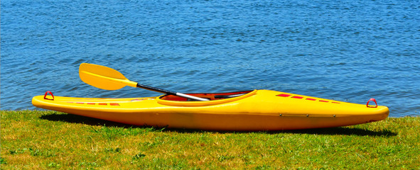 Fototapeta na wymiar Yellow kayak on river bank