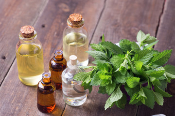 A lot of bottles with essential aroma oil with mint on wooden ba