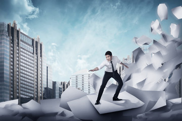 Asian business man surfing on the wave of papers