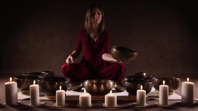 Woman playing a Tibetan bowl, traditionally used to aid meditation in Buddhist cultures
