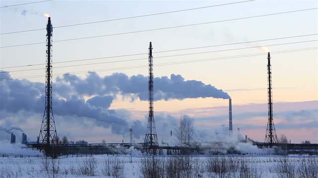 Refinery at sunset sky background. Frosty snowy winter evening. Horizontal panorama