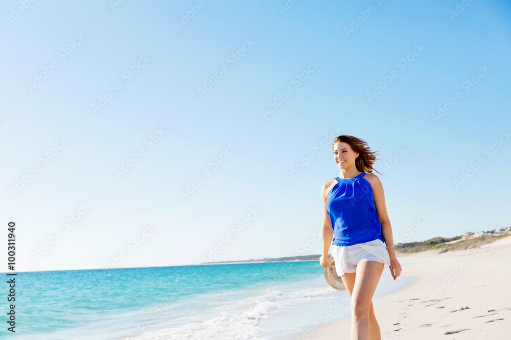 Wall mural young woman walking along the beach