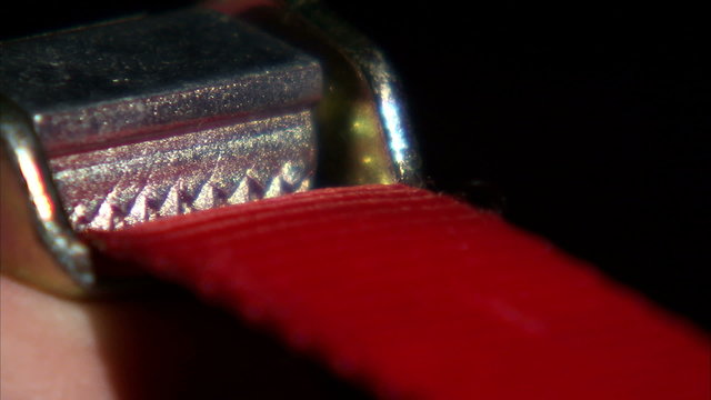 Close up of a red strap going through a cam clamp.