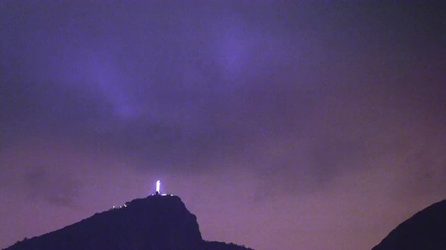 Distant slow pan of Christ the Redeemer statue on top of the Corcovado at night