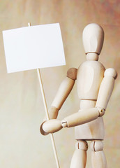 Wooden man model holding blank white poster in its hands. Concept of claims