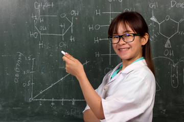 Young women scientist writing molecular structure and pointing on green board