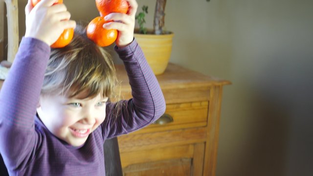 enfant jouant avec des cl&eacute;mentines