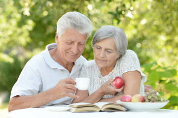 Happy old couple with drink and book