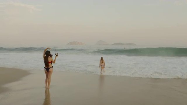 Young woman readies camera to snap photo of friend at the beach