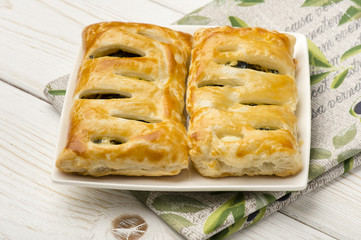 Puff pastry with spinach and feta on the wooden background.