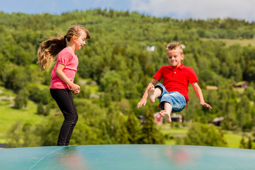 Children bouncing up and down on trampoline
