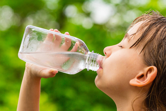 Girl drinking clean tap water from transparent plastic bottle