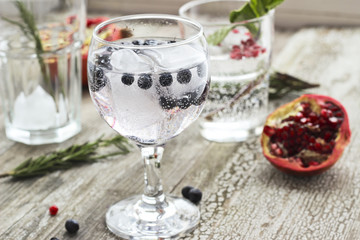Glasses of water with ice, rosemary, mint, pomegranate and blueberry
