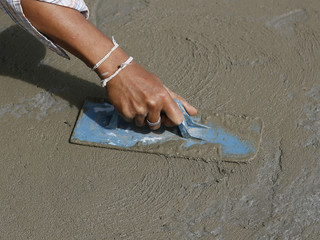 A mason hand finishes a newly poured concrete floor