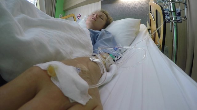 Female Patient Lying in Bed in Hospital with Drop Counter