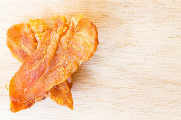 Dried chicken jerky for dogs on wooden background