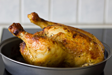 Roasted whole chicken on a baking sheet. Grilled chicken with crispy brown crust.