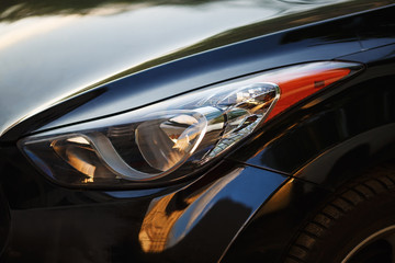 Close-up car headlight of powerful modern black car with glare.