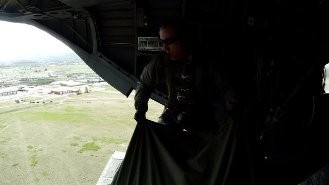 Crew member on a CH-47 Chinook helicopter adjusts something.