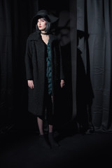 Gothic fashion woman wearing black coat and hat.