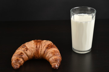 Glass of milk and croissant for breakfast - isolated on black
