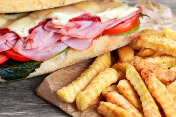 Fried Potatoes and Sandwich with lettuce, slices of fresh tomatoes, salami, hum and cheese.
