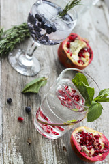 Obraz na płótnie Canvas Glasses of water with ice, rosemary, mint, pomegranate and blueberry