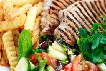 Grilled pork meat  with fried potatoes and vegetables
