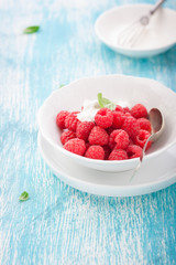 .Fresh raspberries in a white ceramic bowl with metal spoon. closeup, selective focus.