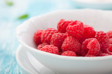 Fresh raspberries in a white ceramic bowl. closeup, selective focus.