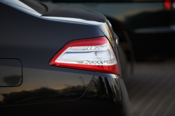 Closeup of a taillight on a modern black car with reflection. Shallow depth of field. Selective focus.