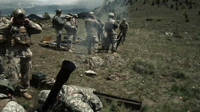 Slow motion clip of soldiers firing a mortar with instuctors.
