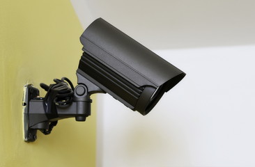 black CCTV camera on the yellow wall