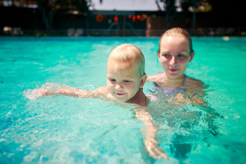 closeup mother small daughter swim smile in azure water of pool