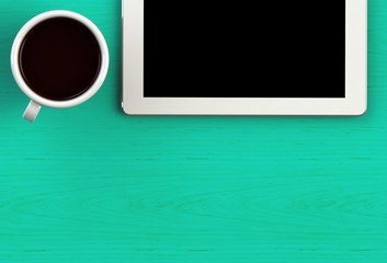 Coffee cup with tablet on green wood table