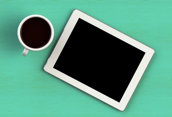 Coffee cup with tablet on green wood table