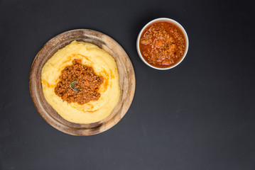 A view from the top of a traditional Polenta with bolognese (ragu) soup on a blackboard surface.