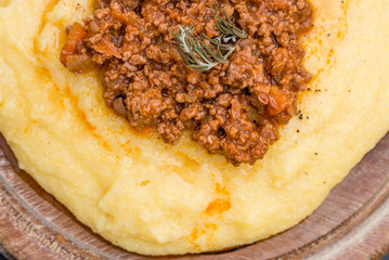 A close up view of a traditional italian dish: Polenta with bolognese soup (ragu)